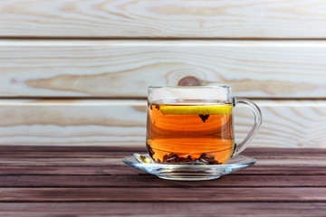 cup of hot tea with tea leaves and lemon on a wooden table