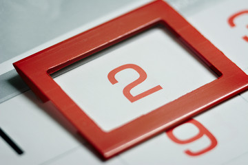 the second day of the month highlighted on the calendar with a red frame close-up macro, a mark on the calendar, the second date