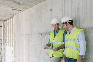 Two workers using tablet on construction site
