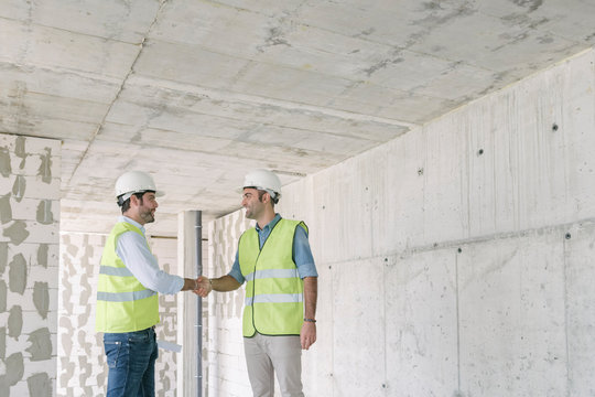 Two workers shaking hands construction site