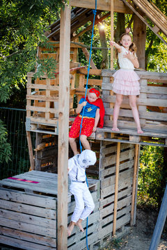 Three kids with superheroes costumes playing on their homemade tree house
