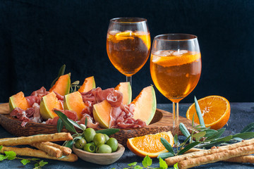 Italian aperitif - aperitivo: prosciutto, melon slices, olives, aperol spritz, grissini