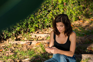 Young woman is using her smartphone in a park