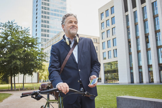 mature, businessman with bicycle in the city - Powered by Adobe