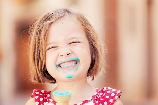 A happy girl eating a blue ice cream