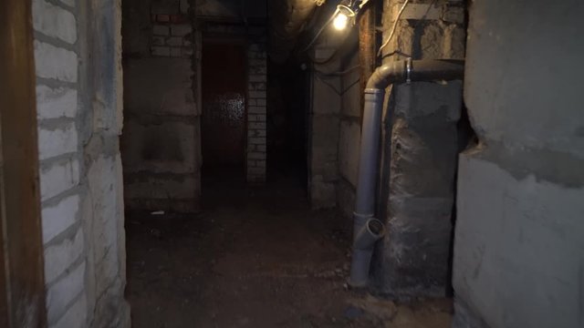 man runs through an old abandoned building, basement with lantern.