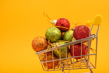 New Year's toys in supermarket trolley on yellow background. Christmas shopping concept