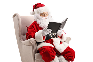 Santa Claus in an armchair and reading a book