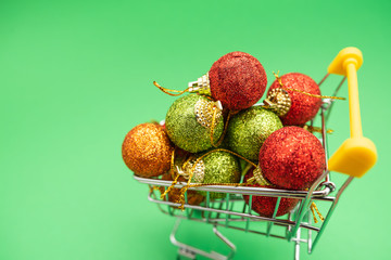 New Year's toys in supermarket trolley on green background. Christmas shopping concept