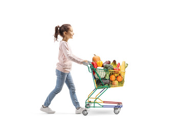 Little girl walking and pushing a shopping cart with fruits and veggies