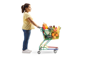 Girl standing with a shopping cart full of fruits and vegetables