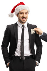 Man putting money into a pocket of a businessman with a santa claus hat