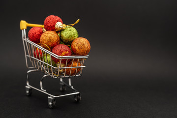 New Year's toys in supermarket trolley on black background. Christmas shopping concept