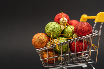 New Year's toys in supermarket trolley on black background. Christmas shopping concept