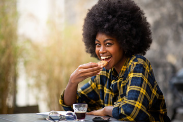 Close up happy young black woman eating cookie