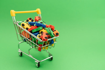 mini toy rubber cars in supermarket trolley on green background