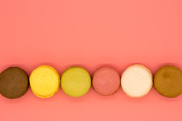 delicious macarons arranged in a row on pink background with copy space