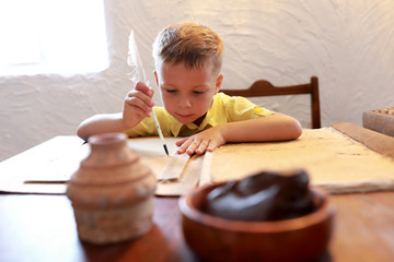 Kid writing with quill pen