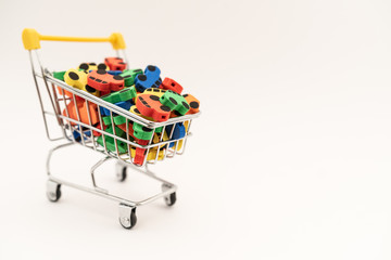 mini toy rubber cars in supermarket trolley on white background
