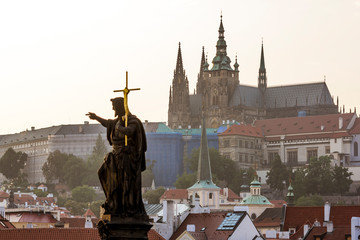Fototapeta na wymiar Sculpture of John the Baptist on Charles bridge against the Prague castle.