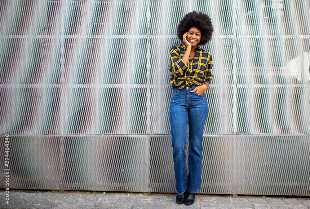 Wall mural Full length stylish young african american woman with afro smiling