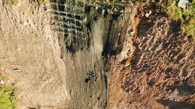 Workers strengthen the slope of the mountain with metal mesh preventing rockfall and landslide on the road, above view. workers constructing anti-landslide concrete wall prevent protect against rock