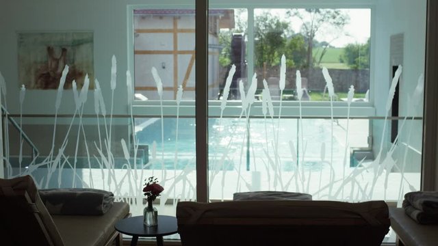 relaxation room next to a pool blankets in a luxurious spa - Ruheraum angrenzend an einen durch eine Glasscheibe abgetrennten Pool mit Liegest&uuml;hlen und Decken in einem luxuri&ouml;sen Spa