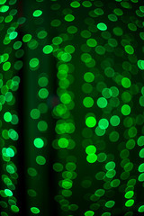 Beautiful festive colored bokeh of glowing circles of green colors. Abstract vertical composition.