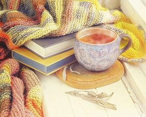 Cup of black tea, sprigs of sage and knitted blanket on windowsill.