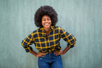 smiling young african american woman with hands on hip