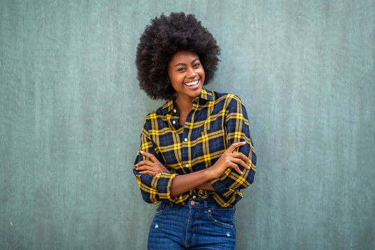 smiling young african american woman with afro hair standing arms crossed