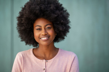 front portrait of beautiful young african american woman with afro by green wall