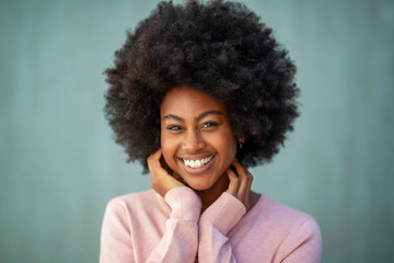 front portrait of attractive young african american woman with afro smiling and hand on face