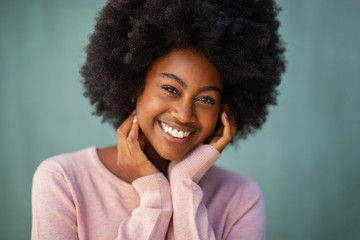 Close up front beautiful smiling young african american woman with afro and hand on face