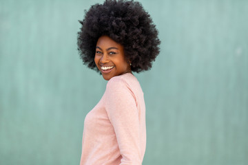Close up side happy young black woman with afro hair against green background