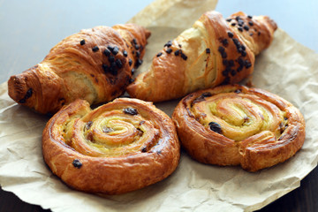Danish raisin swirls and chocolate hazelnut croissants on a piece of paper bag. French pastry.