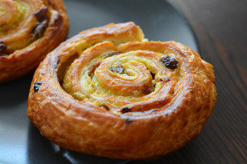 Danish raisin swirls on a black plate. French pastry.