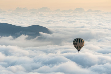 A hot air balloon flies over a sea of clouds in the region of La Garrotxa, in Girona (Spain) at dawn.