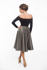 Beautiful elegant young woman with fashion hairstyle and makeup posing on a white background on high heels isolated in a black blouse and satin skirt back view. Free space for text mockup