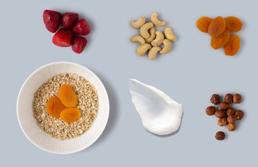 Creative concept still life health diet food photo of bowl dish with healthy breakfast oatmeal corn flackes fruits berries yoghurt on grey background.
