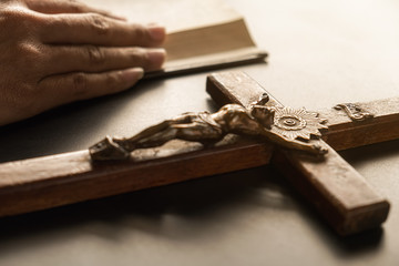 Christian woman praying with hands together on holy bible and wooden cross. Woman pray for god blessing to wishing have a better life and believe in goodness.