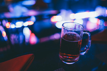 Beer in glass with bar lights behind