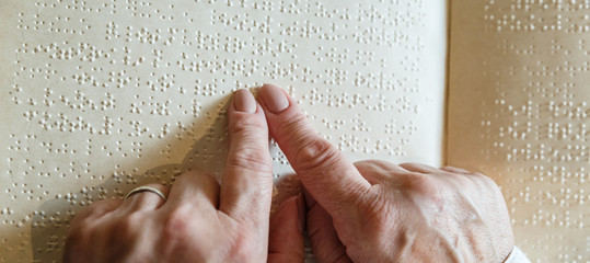 woman reading braille text on old book