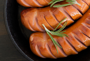 Fried sausages on a cast iron pan.