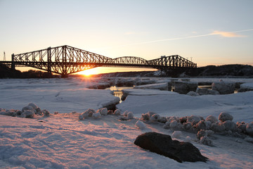 Fototapeta premium Pont de Québec avec glaces sur le fleuve au coucher de soleil vu de la marina St-Romuald (Lévis) Québec, Canada. Quebec bridge with ice on the river at sunset