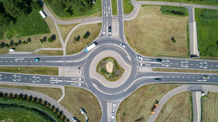 Top down aerial view of a traffic roundabout on a main road in an urban area