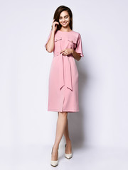 Full length portrait of happy beautiful woman in pink dress posing in studio isolated on white background