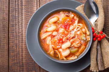 Soup with turkey, pasta, carrot, celery, tomato and cannellini beans, garnished with parmesan cheese, on the table with autumn decoration, Thanksgiving harvest feast, horizontal, top view,  copy space