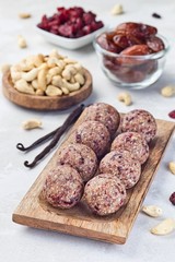 Healthy homemade energy balls with cranberries, cashew nuts, dates and vanilla on a wooden plate,  vertical