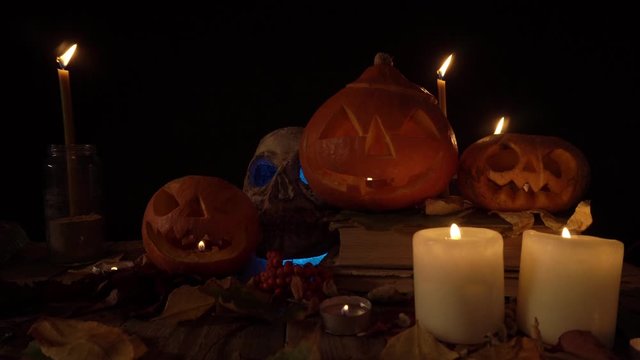 Halloween decorations Jack's lanterns and skull in candlelight, loope video. Theme of autumn holidays, rituals and traditions on Halloween. Craft handmade pumpkin for decoration. Video can be looped.